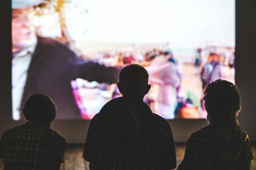 Silhouetted audience watching a large outdoor screen
