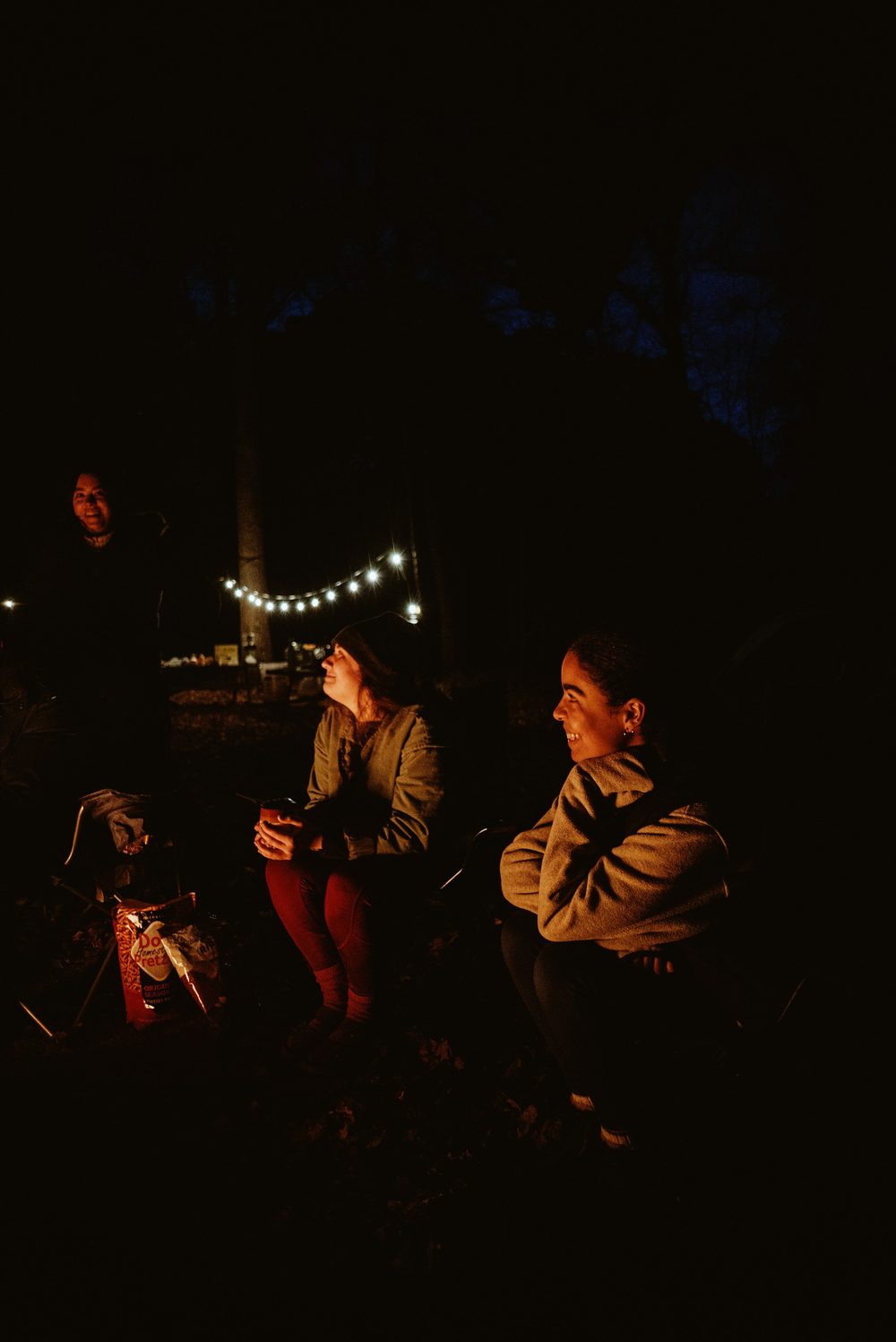 A family wrapped in a blanket together outdoors at night