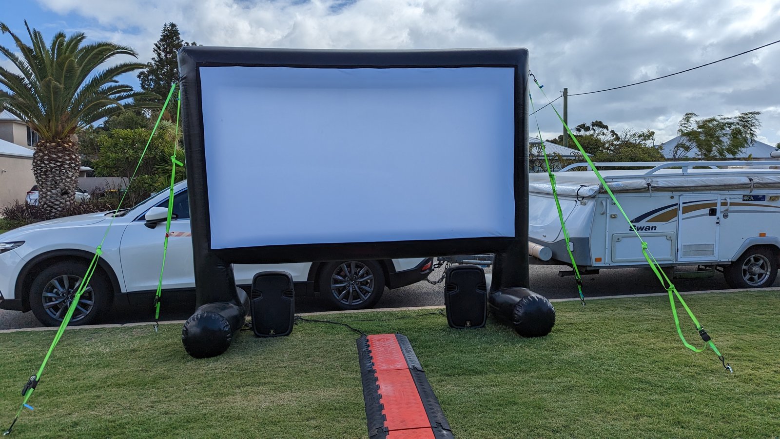 Outdoor cinema hire in Cockburn: large inflatable movie screen with PA speakers on a grassed verge, ready for a community movie night by Perth Pop-Up Movies