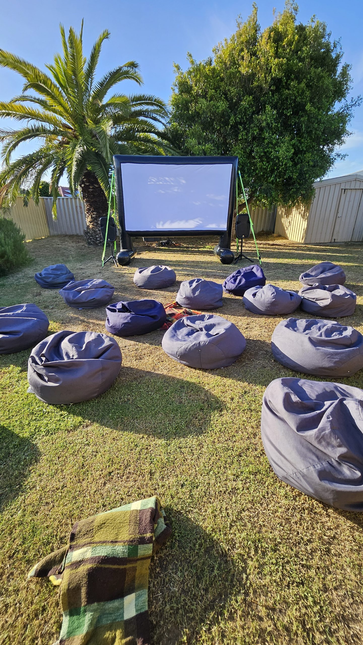 Kids backyard cinema party Perth with inflatable screen and bean bags at night